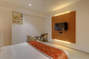 a bedroom with a bed and a tv on the wall at Hotel Diamond 26 in Surat