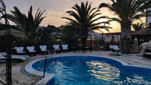 a swimming pool in a resort with palm trees at Agriturismo Reggia Saracena in Agrigento