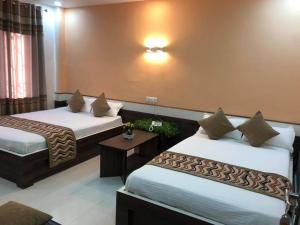 a hotel room with two beds and a table at Yara Hotel in Itahari