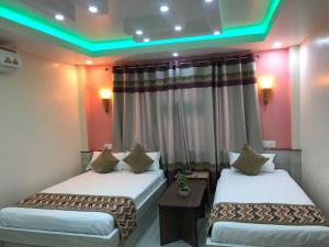 two beds in a hotel room with green lights at Yara Hotel in Itahari