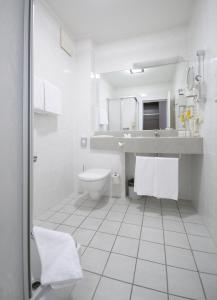 a white bathroom with a toilet and a sink at Best Western soibelmanns Frankfurt Airport in Groß-Gerau