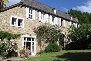 a brick house with white windows and a garden at La Ferme Dagué in Lasseube
