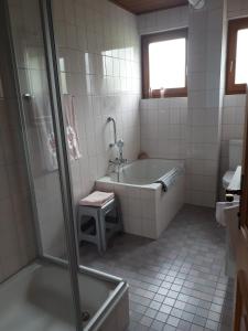 y baño blanco con bañera y ducha. en Ferienhaus Weixelbraun, en Iselsberg