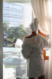 a person dressed in white is looking out of a window at Terme Villa Pace in Abano Terme