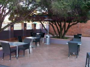 a patio area with chairs, tables and umbrellas at Mackellar Motel in Gunnedah