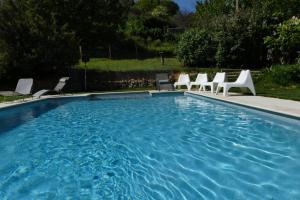 a swimming pool with white chairs and a group at Belle longère au calme - L'auguste maison d'hôtes in Valensole +16 photos