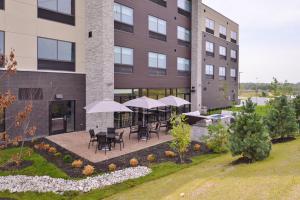un patio extérieur avec des tables et des parasols en face d'un bâtiment dans l'établissement Holiday Inn Express & Suites - Olathe West, an IHG Hotel, à Olathe