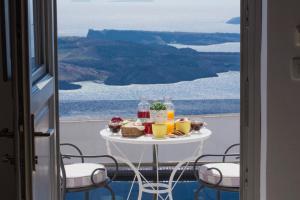 a table with food and drinks on a balcony at Senses Suites in Imerovigli