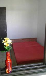 a red vase with flowers in it next to a bed at Magistério para veraneio e descanso in Pinhal