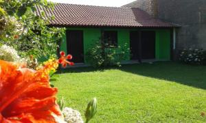 a green house with a yard with a flower in the foreground at Magistério para veraneio e descanso in Pinhal
