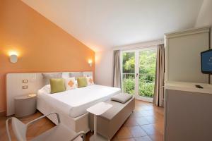 a bedroom with a large white bed and a window at Chia Laguna - Hotel Village in Chia