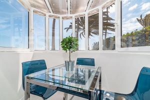 a dining room with a glass table and blue chairs at Stunning Bungalow at the Sand Dunes of Maspalomas in Playa del Ingles
