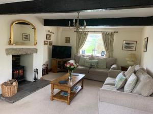 sala de estar con sofá y chimenea en Royds Hall Cottage en Keighley