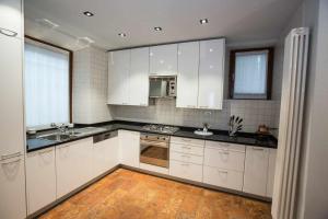 una cucina con armadietti bianchi e ripiani neri di Historical apartment in the center of Gravedona - Larihome A02 a Gravedona