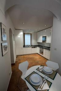 una cucina con tavolo bianco e sedie bianche di Historical apartment in the center of Gravedona - Larihome A02 a Gravedona