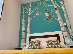 Poo de Cabrales的住宿－Cumbres de los Picos Apartamento Buhos，卧室拥有树木和猫头鹰壁画