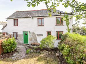 a white cottage with a green door at The Old Coach House in St Austell