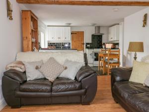 a living room with a leather couch and a kitchen at The Old Coach House in St Austell