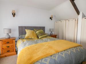 a bedroom with a bed with a yellow blanket at The Old Coach House in St Austell