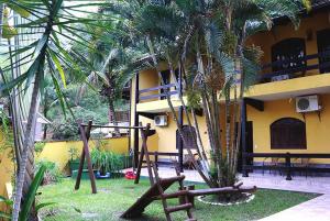 a playground in front of a building with palm trees at Pousada Rio Bracuhy in Angra dos Reis