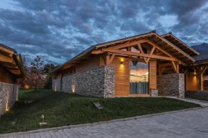 a house with a wooden roof and a stone wall at Mountain Hawk Park in Razlog