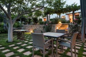 a patio with tables and chairs and a stone wall at Agroturisme Can Planells in San Miguel de Balansat
