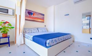 a white bedroom with a bed with a blue comforter at Living Room in Leuca in Leuca