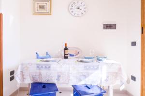 una mesa blanca con una botella de vino y un reloj en Living Room in Leuca, en Leuca