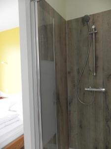 een badkamer met een douche en een houten muur bij Appartement Lily-rose in Cerizay