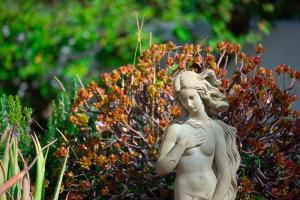 Uma estátua de uma rapariga em frente a um arbusto. em El Molino Estepona em Estepona
