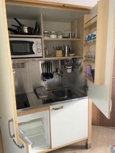 a small kitchen with a sink and a microwave at Casa Genepy - monolocale in centro a Sestriere in Sestriere