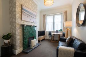 - un salon avec un canapé et une cheminée dans l'établissement Majestic Mansions – Apartments at St Clair, à Dunedin