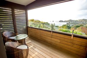 a balcony with a table and chairs and a large window at Cathedral cove and Sunrise in Hahei