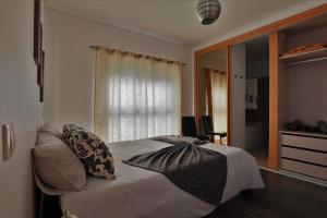 a bedroom with a bed with pillows and a window at Castle in Blue Apartments-Sea View in Sines