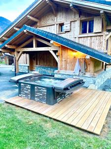 a hot tub on a deck in front of a house at Chalet luxe L'HIBISCUS in Samoëns