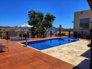 a swimming pool on a wooden deck with a table and an umbrella at Pousada Buena Vista in Capitólio