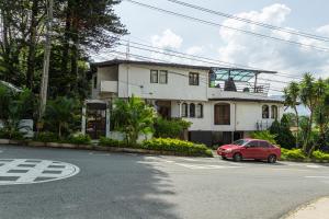 um carro vermelho estacionado em frente a uma casa branca em Ayenda Habana Vieja 1221 em Medellín