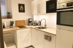 a white kitchen with a sink and a microwave at Gemütliche sanierte 1 Zimmer Wohnung mit privatem Parkplatz im Zentrum in Kiel