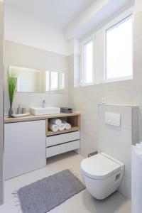 a white bathroom with a toilet and a sink at Flower Square Apartments in Zagreb