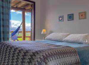 a bedroom with a bed and a window with a view at Pueblo Rosa Norte in Praia do Rosa