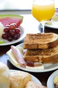 a table with plates of toast and a glass of orange juice at Tezla Hotel in Primavera do Leste