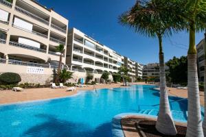 a swimming pool with palm trees in front of a building at Apartamento San Remo Soleado in Palm-Mar