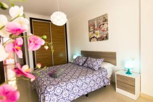 a bedroom with a bed with purple sheets and pink flowers at Apartamento San Remo Soleado in Palm-Mar +13 photos