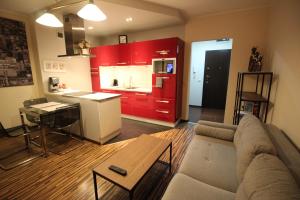 sala de estar con sofá y cocina con armarios rojos. en Apartament Podgórna 12, en Toruń
