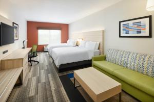 Holiday Inn Express Hotel & Suites Salem, an IHG Hotel في سالم: غرفه فندقيه بسرير واريكه