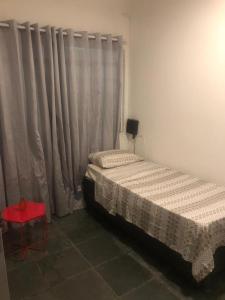 um quarto com 2 camas e um banco vermelho em Pousada Fran em São Paulo