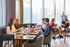 a group of people sitting around a table in a restaurant at Crowne Plaza Christchurch, an IHG Hotel in Christchurch