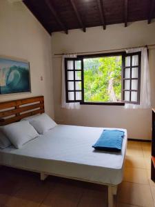 a bedroom with a large bed with a window at Nalua Guest House in Guarda do Embaú