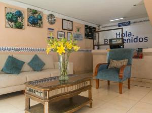 - un salon avec un canapé et un vase de fleurs sur une table dans l'établissement Hotel Express Alejandría, à Xalapa
