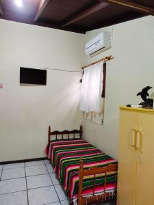 a bedroom with a bed with a colorful blanket on it at Nalua Guest House in Guarda do Embaú